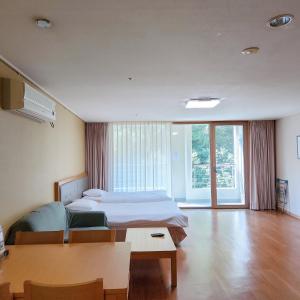 Jeongseon Mayhills Resort في جونغ سون: غرفة نوم بسرير وطاولة في غرفة