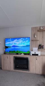 uma televisão de ecrã plano em cima de um centro de entretenimento em madeira em Billing Aquadrome, Kingfisher Meadows 12 em Great Billing