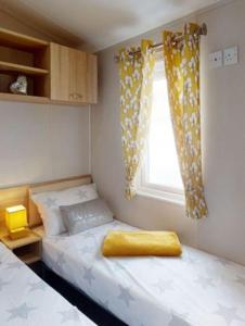 um pequeno quarto com 2 camas e uma janela em Billing Aquadrome, Kingfisher Meadows 12 em Great Billing