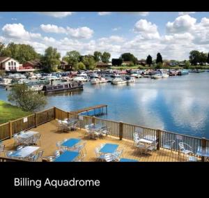 a deck with tables and chairs next to a marina at Billing Aquadrome, Kingfisher Meadows 12 in Great Billing