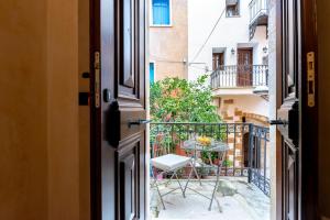 una puerta abierta con una mesa y sillas en el balcón en Oniros Residenza Vecchia, en La Canea 59 fotos más