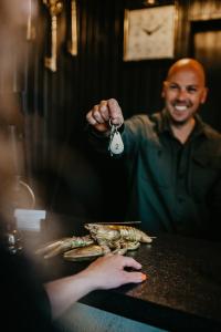 um homem segurando uma chave para uma mesa com comida em Hotel Renesse em Renesse
