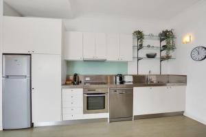 a kitchen with white cabinets and stainless steel appliances at Apartment at Cooper St in Sydney