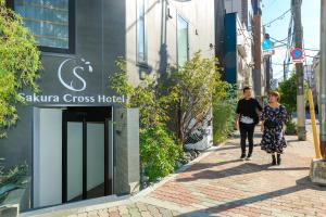 東京的住宿－Sakura Cross Hotel Ueno Iriya Annex，两个女人在建筑物前的街道上走