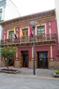 a pink building with flags on a balcony at Morenica del Rosario in Cuenca