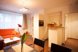 a living room with a orange couch and a kitchen at im 2ten Business Apartments in Vienna