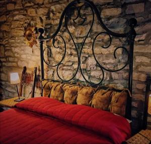 1 cama con manta roja y pared de piedra en B&B Luna e Stelle, en Premilcuore