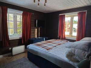 a bedroom with a bed and windows with red curtains at Libeli- panoramaview towards Gaustadtoppen- Jacuzzi in Lona