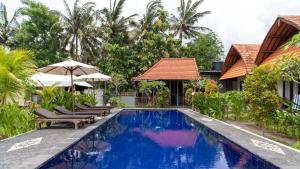 a pool at a resort with chairs and umbrellas at Sindhu Mesari Bungalow in Nusa Penida
