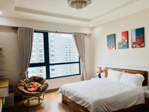 - une chambre avec un lit, une chaise et une grande fenêtre dans l'établissement BOM HOMES- VINHOMES TIMES CITY -3BR- LUXURY APt, à Hanoï 22 autres photos