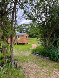 uma casa no meio de um quintal com uma estrada de terra em Mountbatten Shepherds hut & Buckhurst Shepherds hut em Ashford