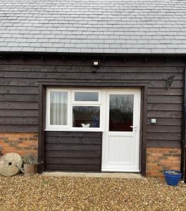 a garage with a white door and a window at Little Buttercup Cottage in Brackley