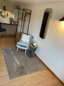 a living room with a chair and a mirror at Little Buttercup Cottage in Brackley