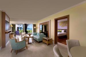ein Wohnzimmer mit einem Sofa und ein Zimmer mit einem Bett in der Unterkunft Dusit Thani Laguna Phuket in Strand Bang Tao