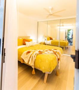 a bedroom with a large yellow bed and a mirror at Coolum Sands Beachside Apartment in Coolum Beach