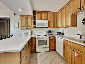 a kitchen with white appliances and wooden cabinets at Aqua Villa #401 in Fort Walton Beach