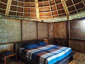 a bed in a room with a wooden ceiling at Pekkae ecolodge and cafe in Libua