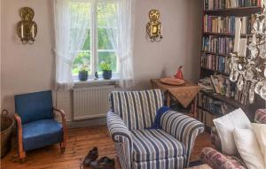 Stunning Home In Rimforsa With Wifi في Rimforsa: غرفة معيشة مع كرسيين ورف للكتب