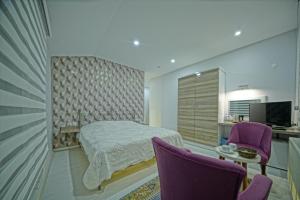 ウチヒサールにあるCappadocia Symbol Hotelのベッドルーム1室(ベッド1台、紫色の椅子2脚付)
