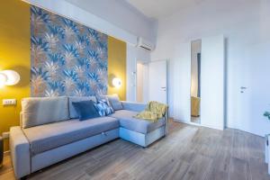 ein Wohnzimmer mit einem blauen Sofa und einem Gemälde in der Unterkunft CaseOspitali - Daimò, delizioso bilocale Fiera perfetto x5 in Bologna