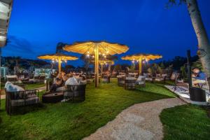 a patio with tables and chairs under umbrellas at night at Cala Sinzias Resort in Castiadas