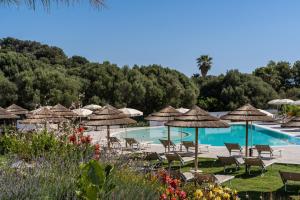 un resort con piscina con sedie e ombrelloni di Cala Sinzias Resort a Castiadas