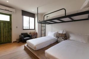 a bedroom with two white beds and a chair at Mini Voyage Hostel in Hualien City