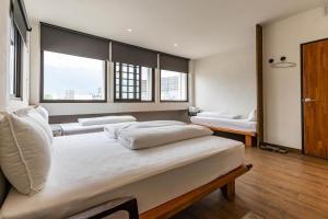 a bedroom with three beds and two windows at Mini Voyage Hostel in Hualien City