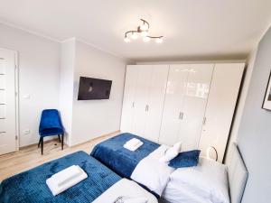 1 dormitorio con 2 camas y silla azul en Apartament Rodzinny Hexagon w Darłówku nad morzem, en Darłowo