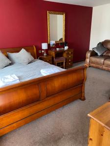 een slaapkamer met een bed, een spiegel en een bank bij The Fountain Oldwood in Tenbury