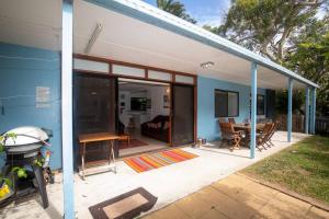 ein blau-weißes Haus mit einer Terrasse mit einem Tisch in der Unterkunft Allamanda Cottage - close to beach - pet friendly in Point Lookout