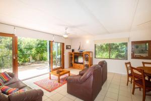 sala de estar con 2 sillas de cuero y mesa en Allamanda Cottage - close to beach - pet friendly en Point Lookout