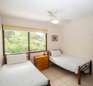 1 dormitorio con 2 camas y ventana en Allamanda Cottage - close to beach - pet friendly en Point Lookout