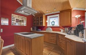 a kitchen with red walls and wooden cabinets at 4 Bedroom Awesome Home In Egernsund in Egernsund