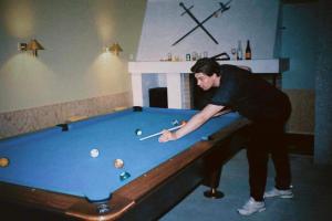 Ein Mann spielt Billard mit einem Queue auf einem Billardtisch in der Unterkunft Balestrand Hotel in Balestrand