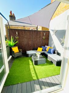 a patio with a couch and a table and grass at The Duplex Margate with Deck, Mini Bar & Air Conditioning in Margate