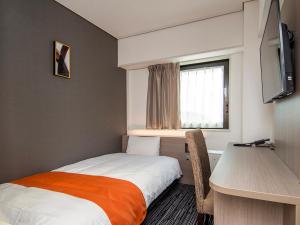 a bedroom with a bed and a desk and a window at Niigata Daiichi Hotel in Niigata