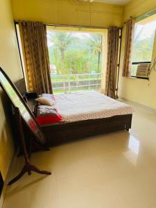 Posto letto in camera con finestra e sedia di Jay 2Bhk Villa Alibaug ad Alibaug