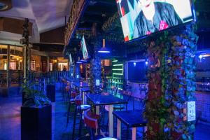 a bar with tables and chairs and a tv on a wall at The Luke Hotel - Roasters in Nairobi