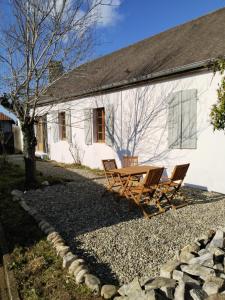 a table and chairs in front of a white building at Maison de l'enfant gites 