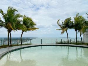 uma piscina com palmeiras e o oceano em Seaview Suite SS Melaka by BetaStay em Malaca