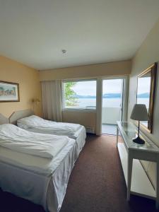 a hotel room with two beds and a table and windows at Balestrand Hotel in Balestrand