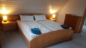 a large wooden bed with two blue chairs on it at Haus am Scharpenmoor in Norderstedt