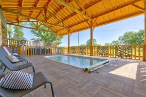 une grande terrasse avec une piscine et une pergola en bois dans l'établissement Le Cabanot, à Peyrusse-Grande