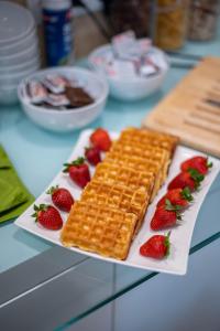 a plate of waffles and strawberries on a table at sHome Hotel Graz - Self-Check-in & free parking in Graz