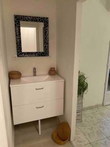 ein Badezimmer mit einem weißen Waschbecken und einem Spiegel in der Unterkunft studio cosy 40m2 in Warlus