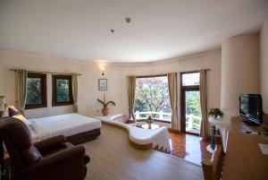 a bedroom with a large bed and a living room at Imperial Phukaew Hill Resort in Khao Kho