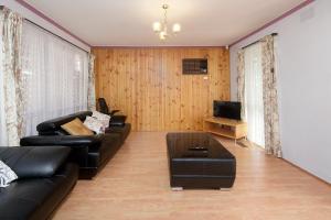 sala de estar con sofá de cuero negro y TV en Beautiful Family home, en Doveton