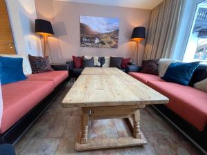 salon z drewnianym stołem i czerwonymi kanapami w obiekcie Villa Augustine In Hinterglemm Zentrum w Saalbach Hinterglemm