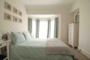 a white bedroom with a bed and a window at Tŷ Glas, Fishguard, Ideal for beach, coastal path and town! in Fishguard